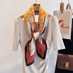 Detail of silk scarf with orange horse bit pattern tied on a dress for styling