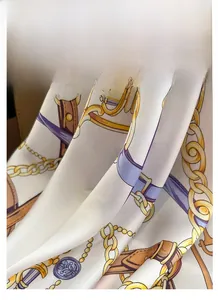 Gros plan d'un foulard en satin avec imprimés chaînes dorées et cuir marron