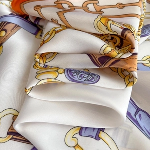 Détail d'un foulard en satin de soie avec motifs équestres et chaîne en crème et violet