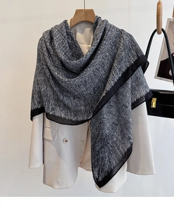 Detail of a black and white geometric silk scarf draped over a white suit blazer