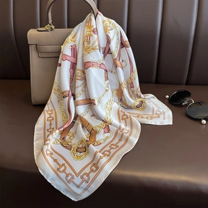 Détail d'un foulard en soie à imprimé chaîne drapé sur un sac à main en cuir