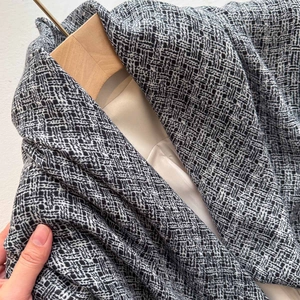 Close-up of black and white tweed texture on premium spring coat with smooth beige lining