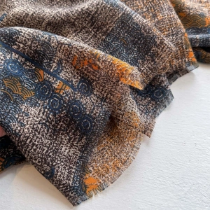 Ethnic style geometric pattern shawl with fringe edges on light textured surface