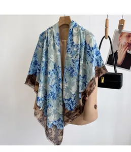 Detail of floral print on blue and beige scarf with fringed edges and soft cotton texture