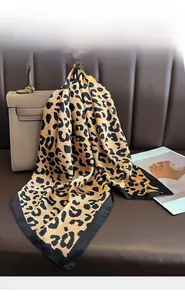Detail of silk leopard print scarf with black borders draped over a luxury handbag
