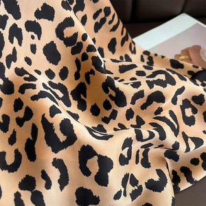 Macro view of leopard print silk scarf fabric showing glossy texture and fine black trim