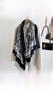 Detail of a large black and white floral scarf styled over a beige blazer jacket