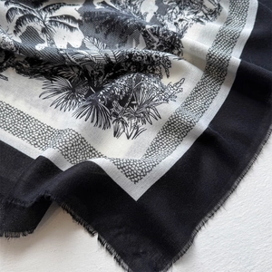 Detail of a tropical palm tree print scarf with soft texture and frayed edge finish