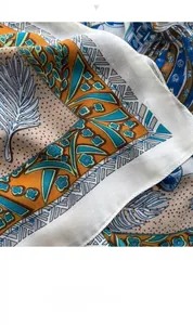 Close-up of printed silk scarf featuring vibrant feather and floral patterns