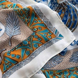 Close-up of silk scarf with intricate feather patterns and vibrant floral borders