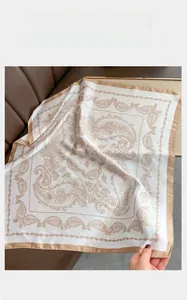 Detailed close-up of pearl white paisley silk scarf with champagne gold border finish