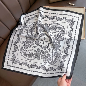 Macro detail of elegant black and white paisley silk scarf with premium satin texture