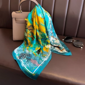 Silk satin square scarf with mountain art print draped over a stylish brown handbag
