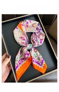 Detail of folded paisley print faux silk scarf displayed on a black rectangle tray