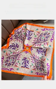 Detail of paisley print silk scarf with vibrant orange and purple tones on leather