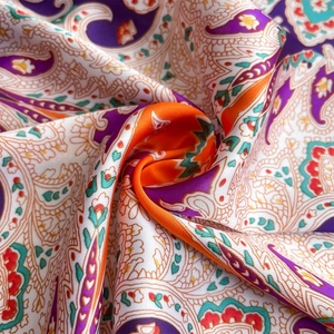 Macro shot of paisley silk scarf showing soft orange and purple fabric texture and folds