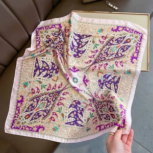 Detail of silk-like square scarf with vintage paisley print draped on a leather sofa