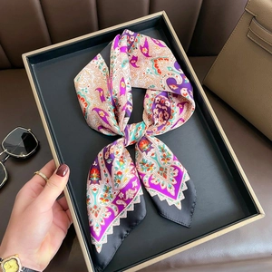 Elegant purple paisley silk scarf neatly folded in a gold-rimmed tray with luxury background