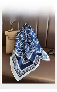 Close-up of geometric silk-like square scarf draped elegantly over a brown leather handbag