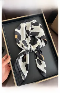 Close-up of a leopard print satin silk square scarf tied in a bow on a display tray