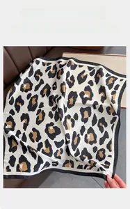 Detail of elegant leopard print silk scarf with black hem on leather background