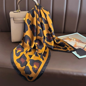 Elegant leopard print satin square scarf in yellow and black tied on a handbag