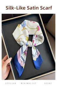 Detail of elegant chain and flower print satin silk scarf tied in a bow on tray