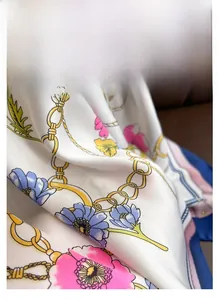 Detailed close-up of printed satin scarf showing golden chains and floral patterns