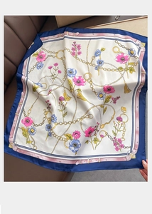 Detailed view of floral and golden chain patterns on a navy blue satin silk scarf