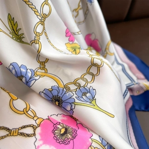 Detailed macro view of the satin scarf with golden chain and colorful floral pattern