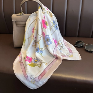 Elegant floral chain print silk scarf draped over a designer handbag with sunglasses