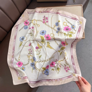 Close-up of elegant floral print satin scarf with golden chain details and tassel elements