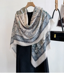 Close-up of beige cashew flower printed shawl with fringed edges on a wooden hanger