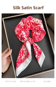Detailed view of red floral silk satin square scarf tied in a bow on a black tray