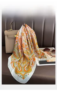 Detail of bohemian paisley silk scarf draped over a bag with luxury lifestyle props