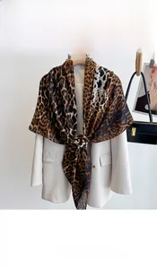 Close-up of leopard print silk scarf draped over a white blazer with a smooth texture