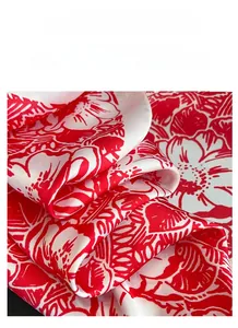 Detailed close-up of white silk scarf fabric with elegant red floral patterns and glossy texture
