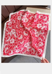 Close-up of lightweight silk scarf featuring vibrant red floral prints and flat hemmed edges
