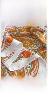 Detailed view of vibrant paisley silk scarf showing premium edge stitching and texture