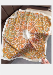 Macro view of silky paisley square scarf featuring orange and green vintage patterns