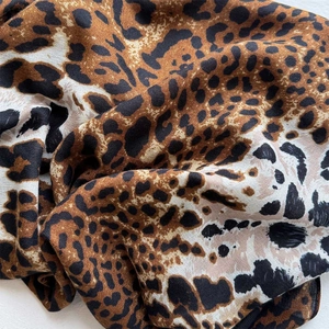 Close-up of leopard print silk scarf fabric showing soft texture and glossy finish