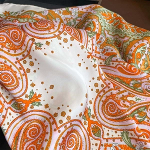 Macro shot of paisley silk scarf showing luxury texture and vibrant orange patterns
