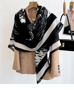 Detail of black and white leopard print scarf draped over a beige blazer with fashion props