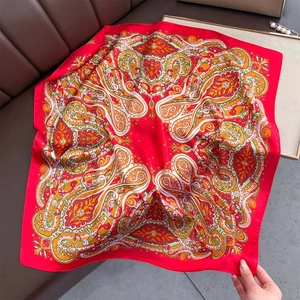 Macro shot of red paisley silk scarf texture on leather surface showing satin sheen