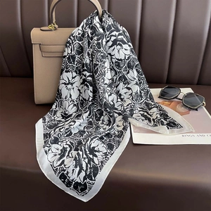 Elegant black and white floral silk scarf draped over a classic bag for a stylish look