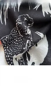 Macro detail of high-quality leopard print fabric on a black and white square scarf