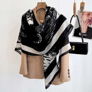 Elegant black and white leopard print square scarf draped over a beige blazer for women