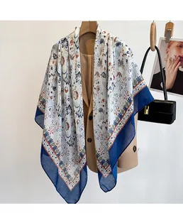 Detail of floral printed scarf with navy blue borders styled on a khaki blazer jacket