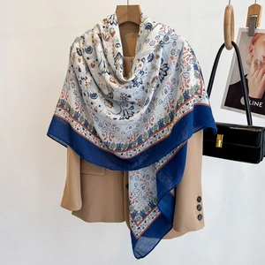 Printed large scarf with paisley patterns draped over a blazer for elegant travel styling