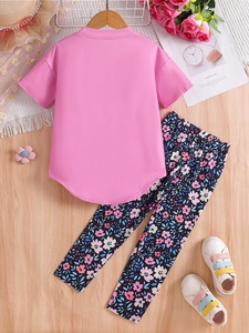 Toddler girl summer outfit with pink t-shirt and floral leggings on wooden background